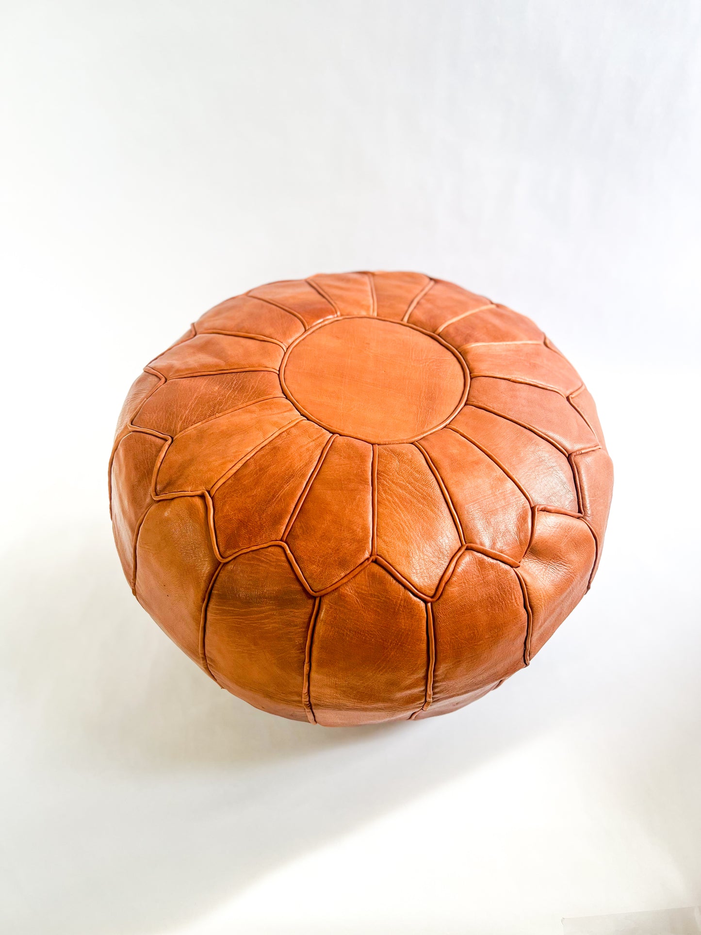 Hand-stitched round Moroccan leather pouf in natural tan, perfect as an ottoman or extra seating.
